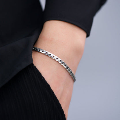 Silver bracelet on a person's wrist against a neutral background